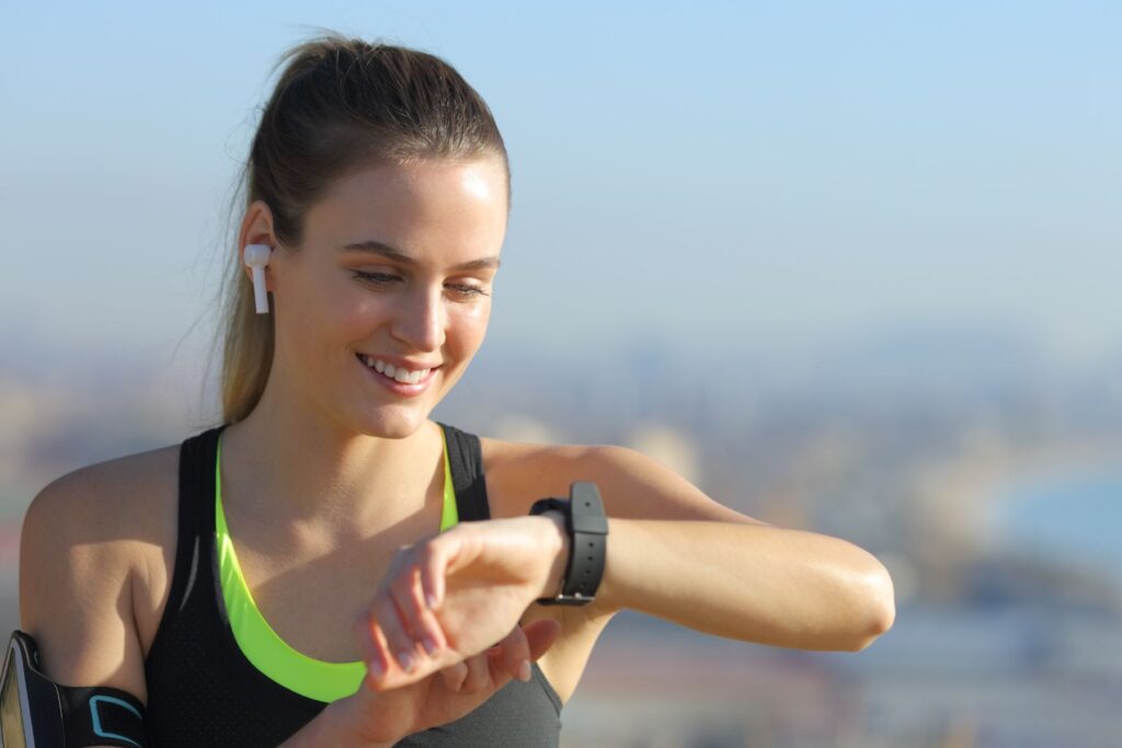 Female runner looking at watch wearing earbuds