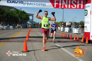 Man with arms up crossing finish line at race