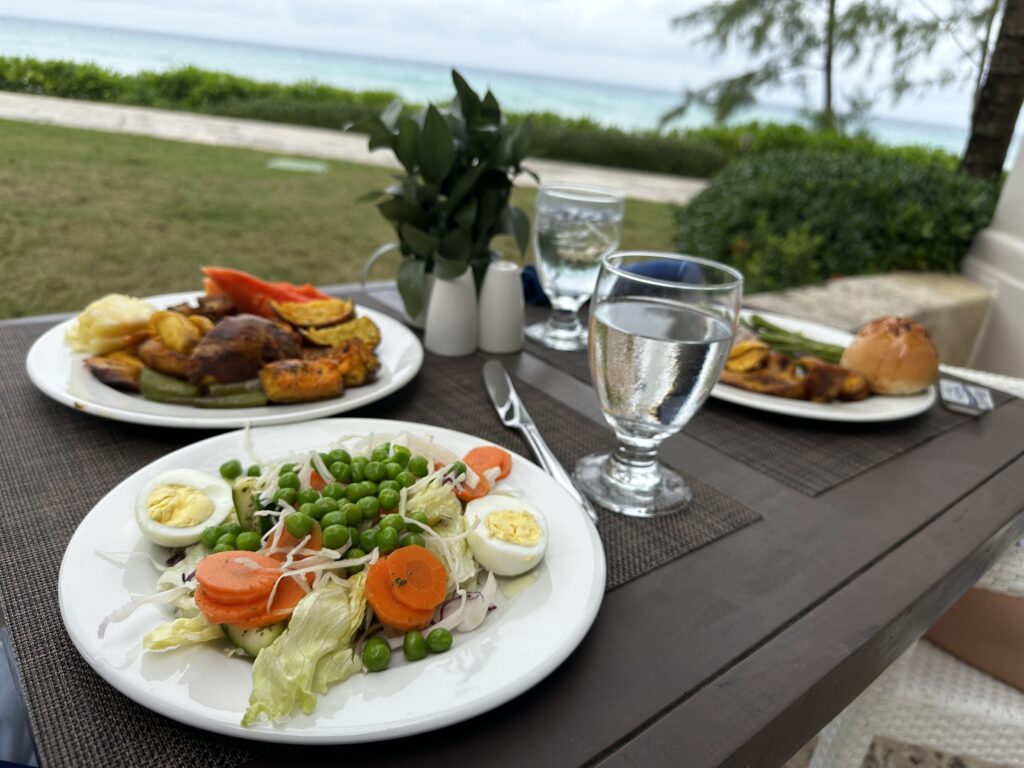 Plates with fresh fruits and vegetables outside overlooking ocean