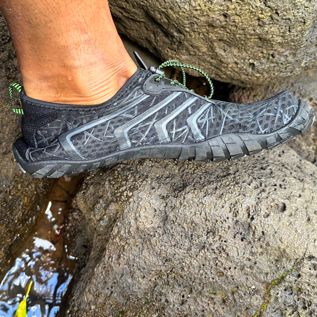 Man hiking over a rock in water shoe