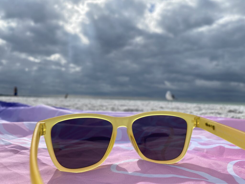 Yellow Goodr sunglasses on the beach