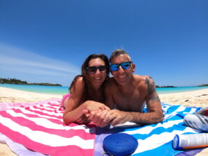 Couple on pink and white and blue and white striped beach towels